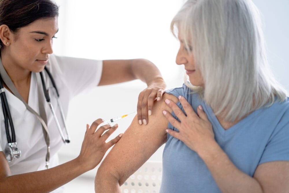A-woman-confidently-looks-on-as-a-medical-professional-injects-her-with-a-dose-of-vaccine.
